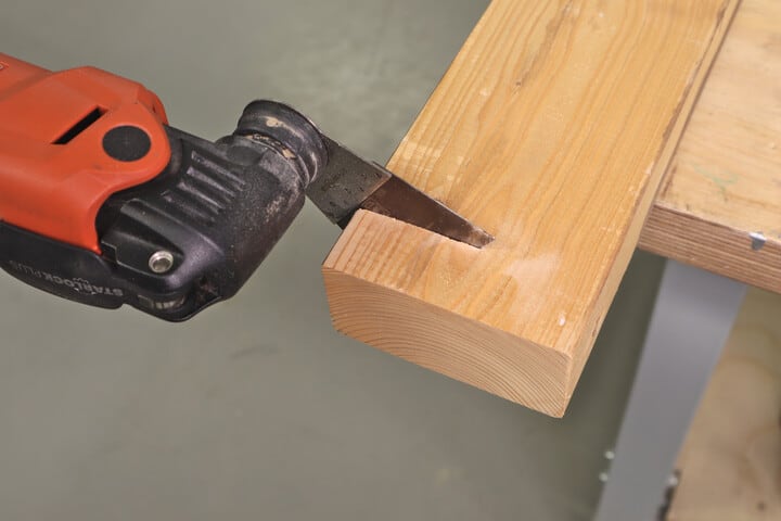 An oscillating multi-tool cutting a piece of two-by-four dimensional lumber